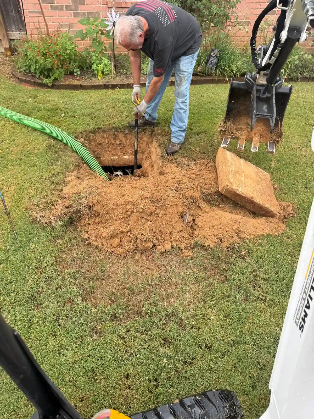 Crew member preparing an excavated septic tank access for service