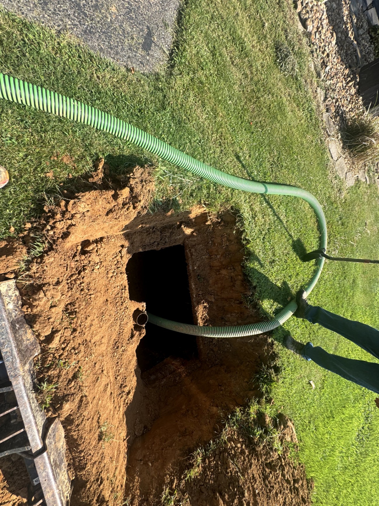 Pump hose drawing waste from an open septic tank on a West Tennessee job