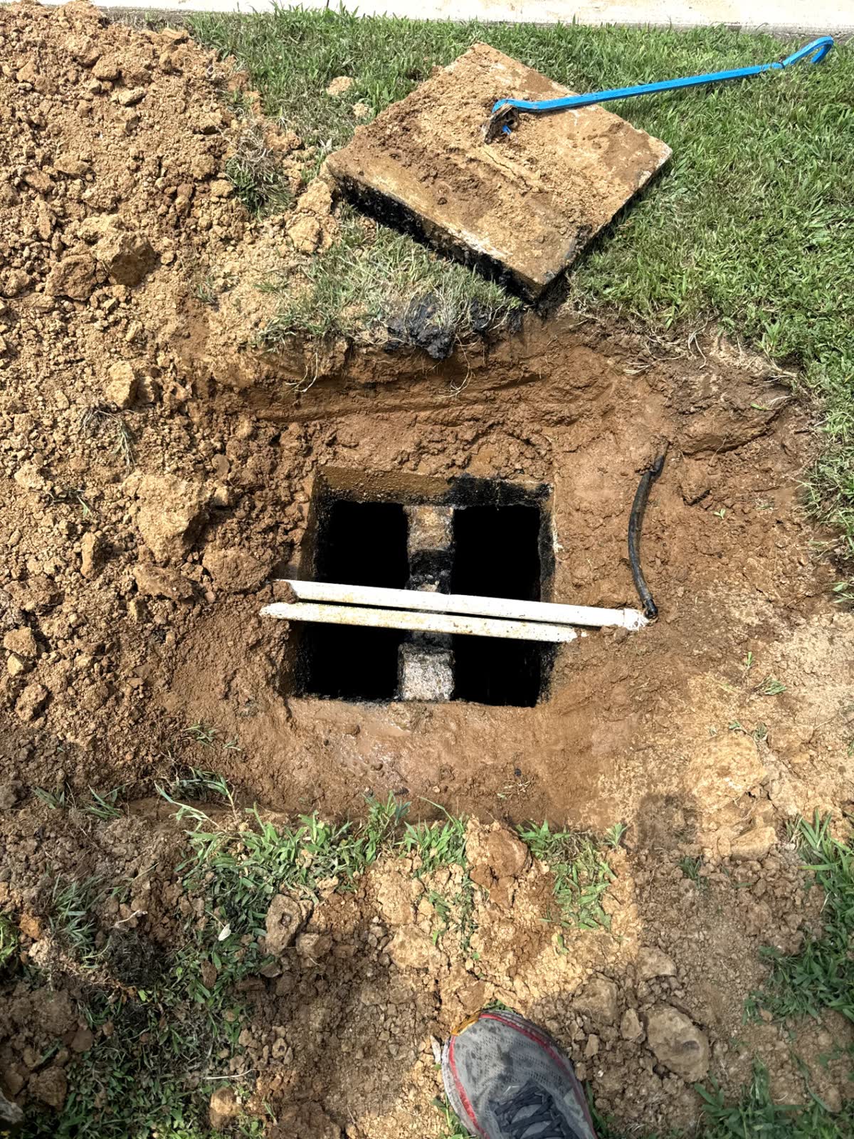 Concrete septic tank opened for inspection with inlet and outlet baffles visible
